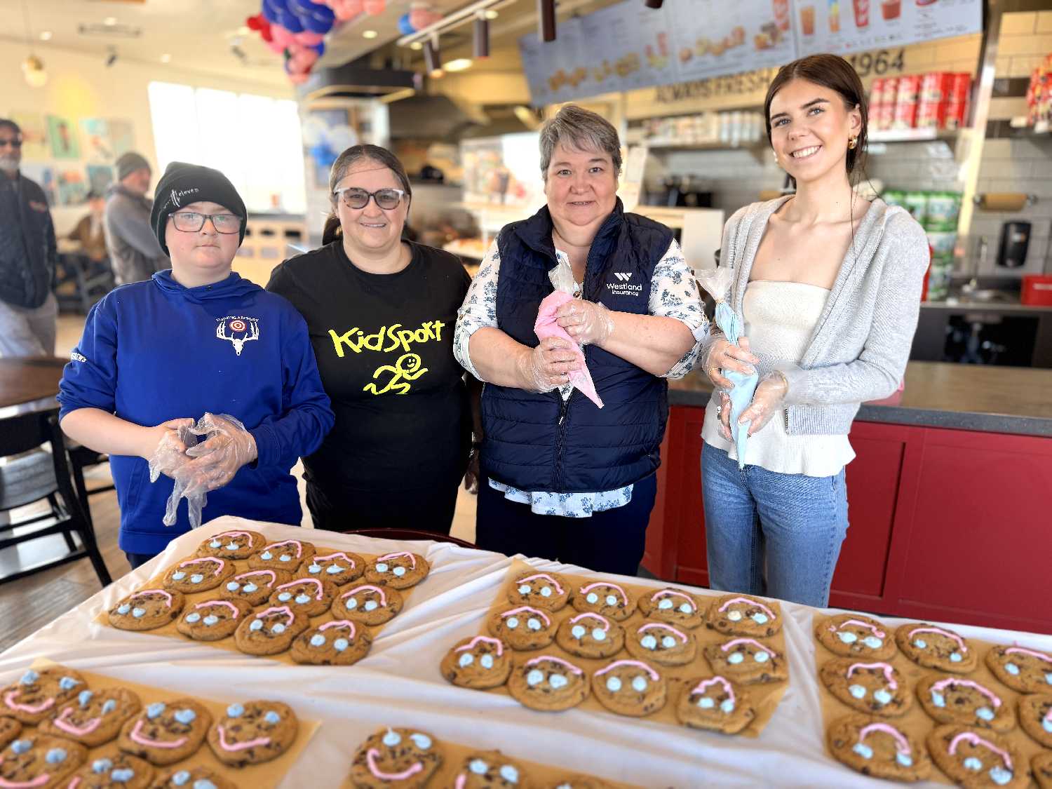 Alexyn Andrews, Beth Oslund with KidSport Whitewood, Moosomin and Area, Tannis Rohatyn from Westland Insurance in Wawota, and Joey Light from the World-Spectator in Moosomin decorating Smile Cookies in Moosomin last week. Proceeds from last week�s Smile Cookie sales went to KidSport.
